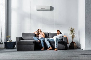 Çekici kız arkadaş ve yakışıklı erkek arkadaş evdeki kanepede oturuyor. 