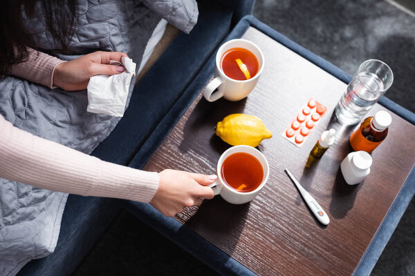 cropped view of sick woman taking cup of tea 