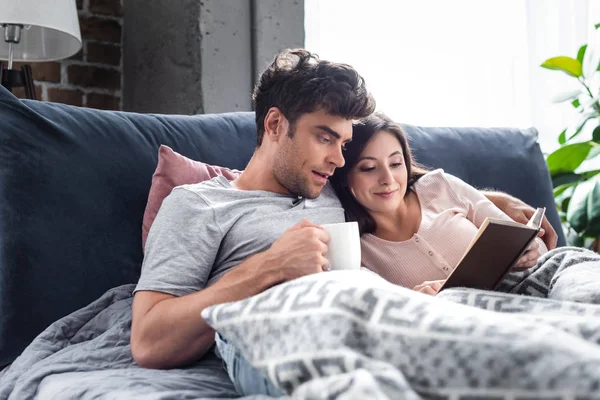 Vriendin Lezen Boek Vriendje Holding Kopje Thee — Stockfoto