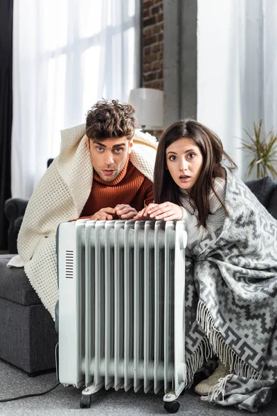 迷人的女朋友和男朋友在加热器旁被空旷的暖气覆盖着 — 图库照片