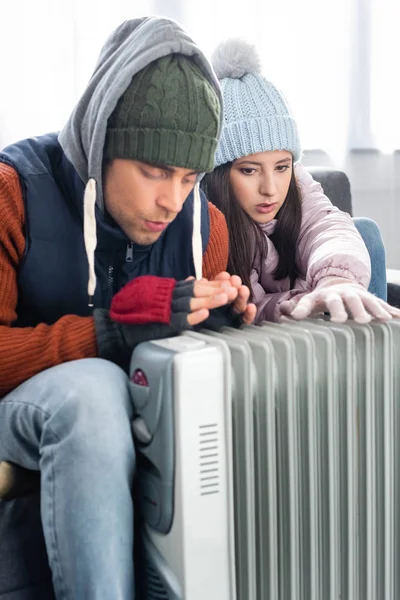 穿着冬装的漂亮女友和男朋友在加热器边热身 — 图库照片