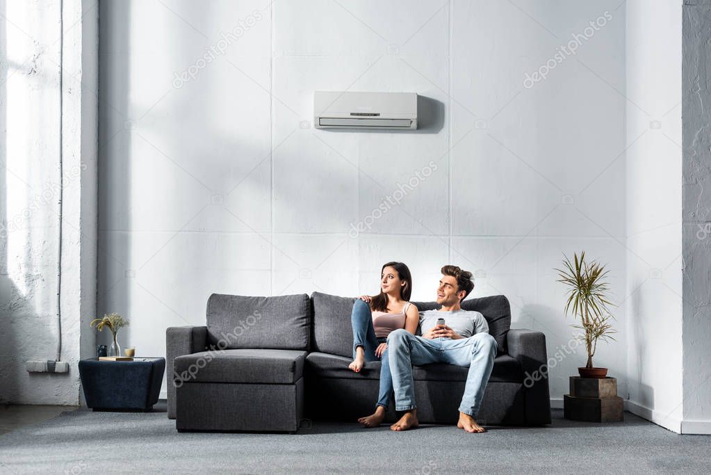 Attractive girlfriend and handsome boyfriend sitting on sofa in apartment