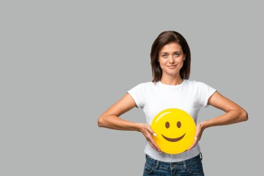 Kyiv, Ukrayna - 10 Eylül 2019: Gri üzerinde izole edilmiş, sarı gülümseyen emoji tutan güzel kadın