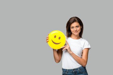 Kyiv, Ukrayna - 10 Eylül 2019: Gri üzerinde izole edilmiş, sarı gülümseyen emoji tutan neşeli kadın