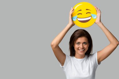Kyiv, Ukrayna - 10 Eylül 2019: Gri renkli, gülen sarı emojiyi tutan güzel bir kadın.