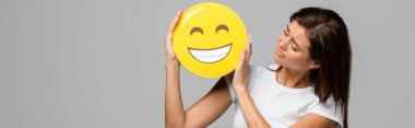 Kyiv, Ukrayna - 10 Eylül 2019: Gri renkli, mutlu, sarı gülümseyen emojiyi tutan esmer kadın
