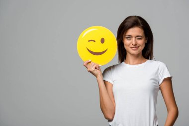 Kyiv, Ukrayna - 10 Eylül 2019: Gri renkte izole edilmiş sarı göz kırpan emoji tutan güzel bir kadın.