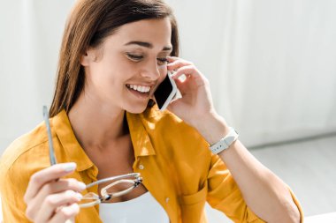 Gözlüklü neşeli serbest çalışan ve ofisteki akıllı telefondan konuşan.