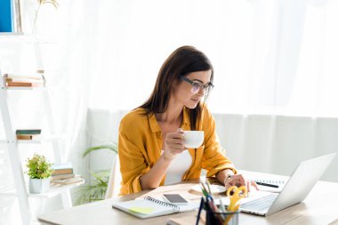 Bilgisayarında kahve fincanıyla çalışan güzel bir serbest yazar.