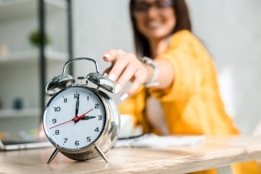 selective focus of female freelancer touching alarm clock clipart