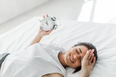 Güzel, mutlu bir kadın sabahın köründe çalar saatle yatakta yatıyor.