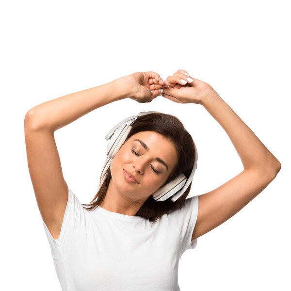 dreamy woman with closed eyes listening music with headphones, isolated on white