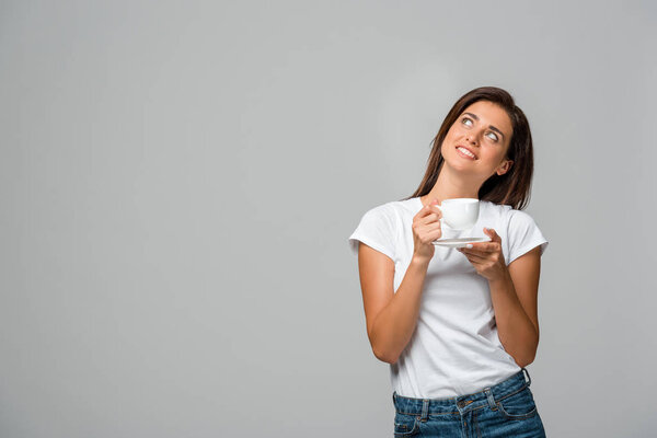 dreamy smiling girl holding cup of coffee, isolated on grey