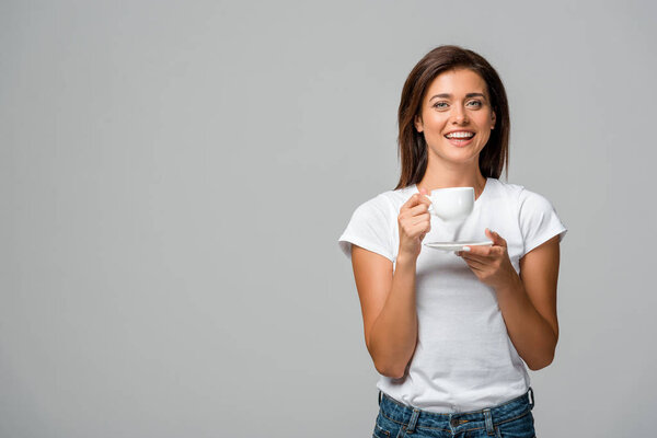 beautiful smiling woman holding cup of coffee, isolated on grey