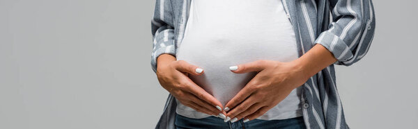 partial view of pregnant woman touching tummy isolated on grey