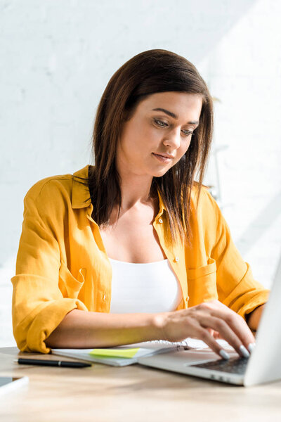 beautiful freelancer typing on laptop in home office