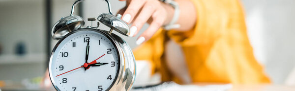 cropped view of woman touching alarm clock