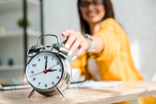 selective focus of female freelancer touching alarm clock