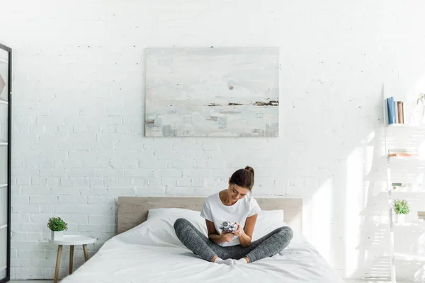 Happy Girl Sitting Alarm Clock Bed Morning — Zdjęcie stockowe