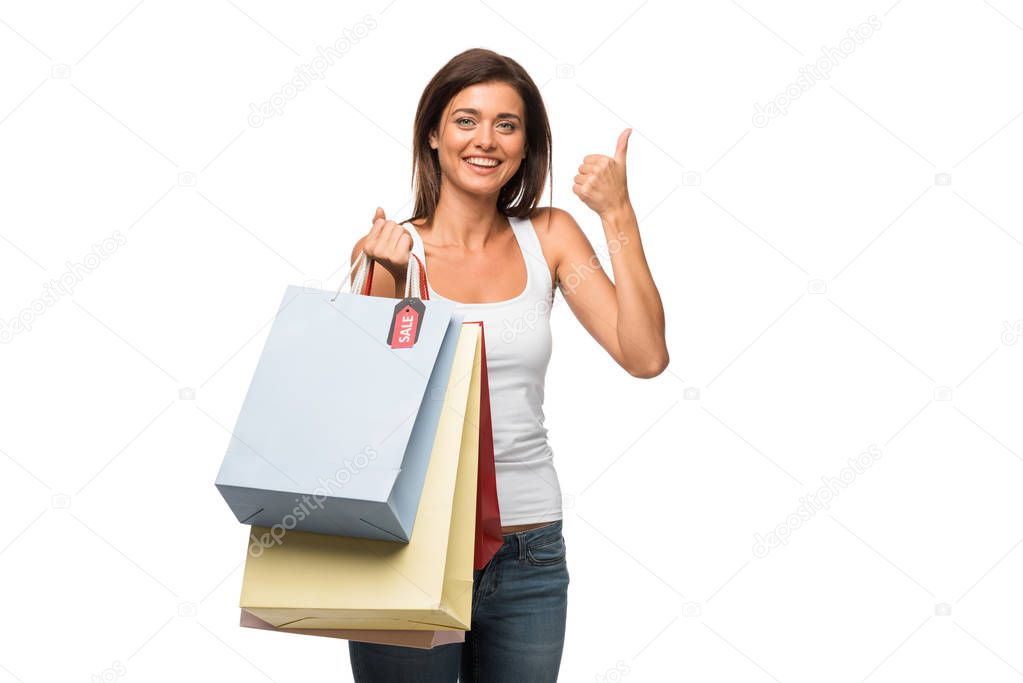 beautiful girl holding shopping bags with sale signs while showing thumb up, isolated on white 