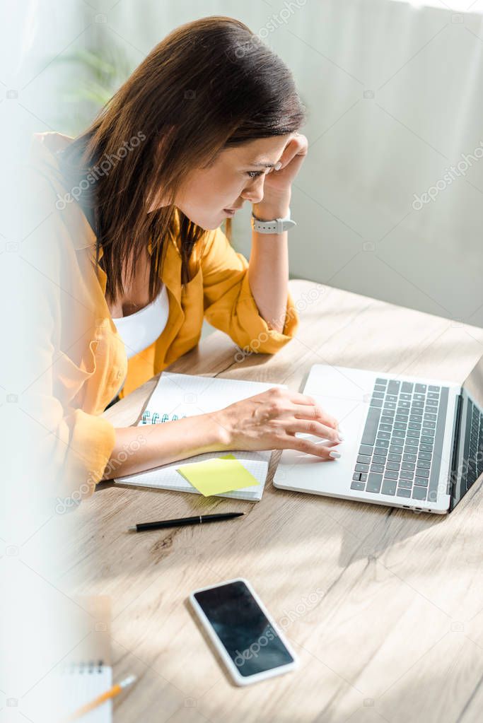 beautiful concentrated freelancer working on laptop in home office
