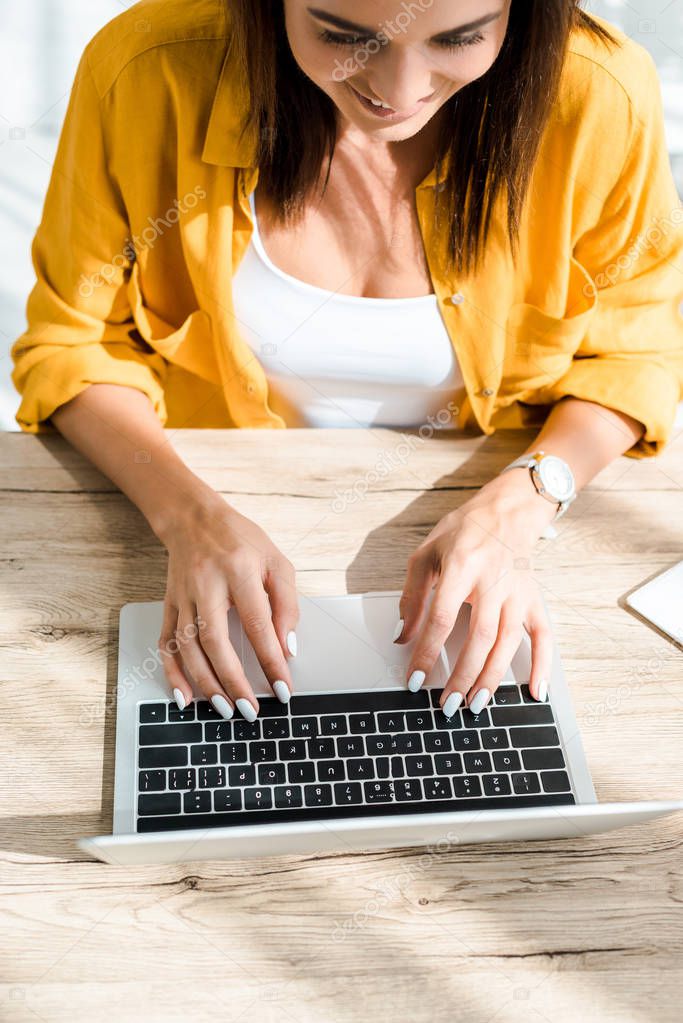 attractive smiling freelancer working on laptop in home office