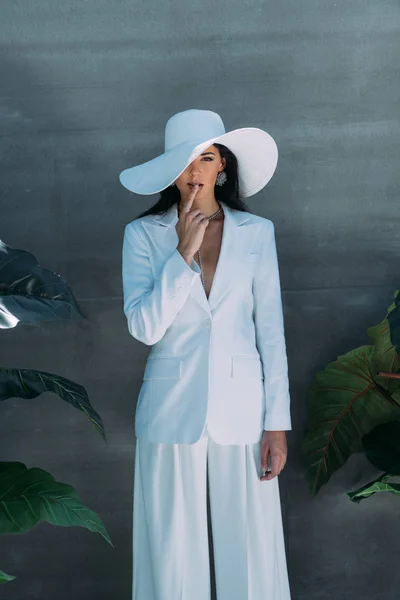 白いスーツの魅力的な女性と外でポーズをとって顔を隠す帽子 — ストック写真