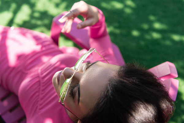 high angle view of attractive woman in dress and sunglasses posing outside 