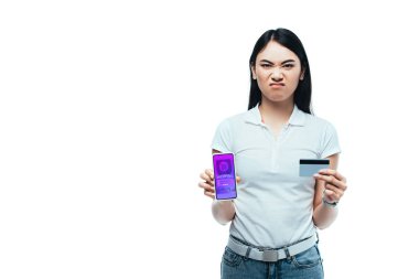 Online alışveriş uygulaması olan kredi kartı ve akıllı telefonu olan hoşnutsuz esmer Asyalı kız beyazdan izole edilmiş.