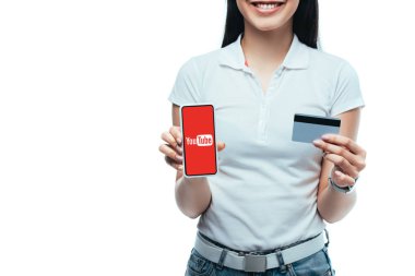 Kyiv, Ukrayna - 15 Temmuz 2019: elinde kredi kartı ve akıllı telefon bulunan gülümseyen esmer Asyalı kızın görüntüsü beyaz ekranda izole edilmiş.