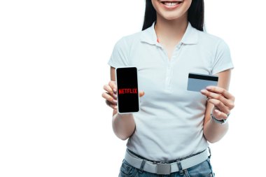 Kyiv, Ukrayna - 15 Temmuz 2019: elinde Netflix uygulaması olan gülümseyen esmer Asyalı kız, elinde kredi kartı ve akıllı telefon tutuyordu.