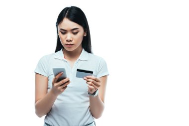 Asyalı ciddi bir esmer kız kredi kartı ve akıllı telefon tutuyor.