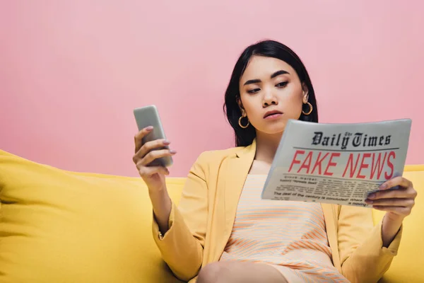 Σοβαρή Ασιατική Γυναίκα Κρατώντας Εφημερίδα Ψεύτικα Νέα Και Smartphone Κίτρινο — Φωτογραφία Αρχείου