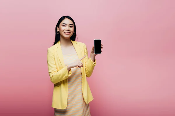 Happy Asian Woman Yellow Outfit Pointing Finger Smartphone Blank Screen — Stock Photo, Image