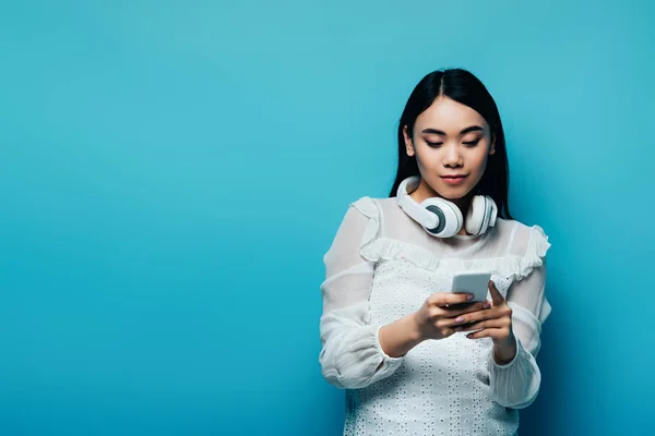 Asian Woman Wireless Headphones White Blouse Using Smartphone Blue Background — Stock Photo, Image