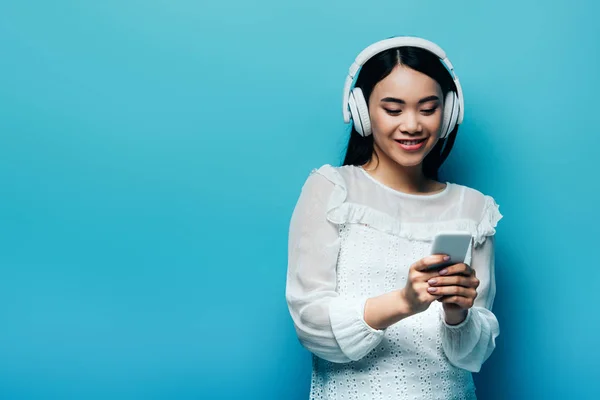 Sonriendo Mujer Asiática Con Auriculares Usando Teléfono Inteligente Sobre Fondo —  Fotos de Stock