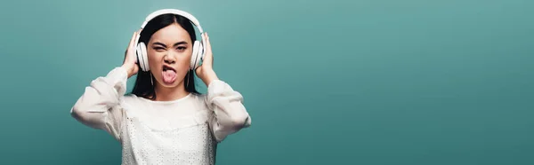 Kulaklıklı Asyalı Kadın Yeşil Arka Planda Yüzünü Buruşturuyor Panoramik Çekim — Stok fotoğraf