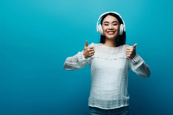 Wanita Asia Tersenyum Dengan Headphone Menunjukkan Jempol Latar Belakang Biru — Stok Foto