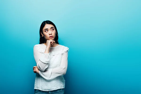 Doordachte Brunette Aziatische Vrouw Zoek Weg Blauwe Achtergrond — Stockfoto