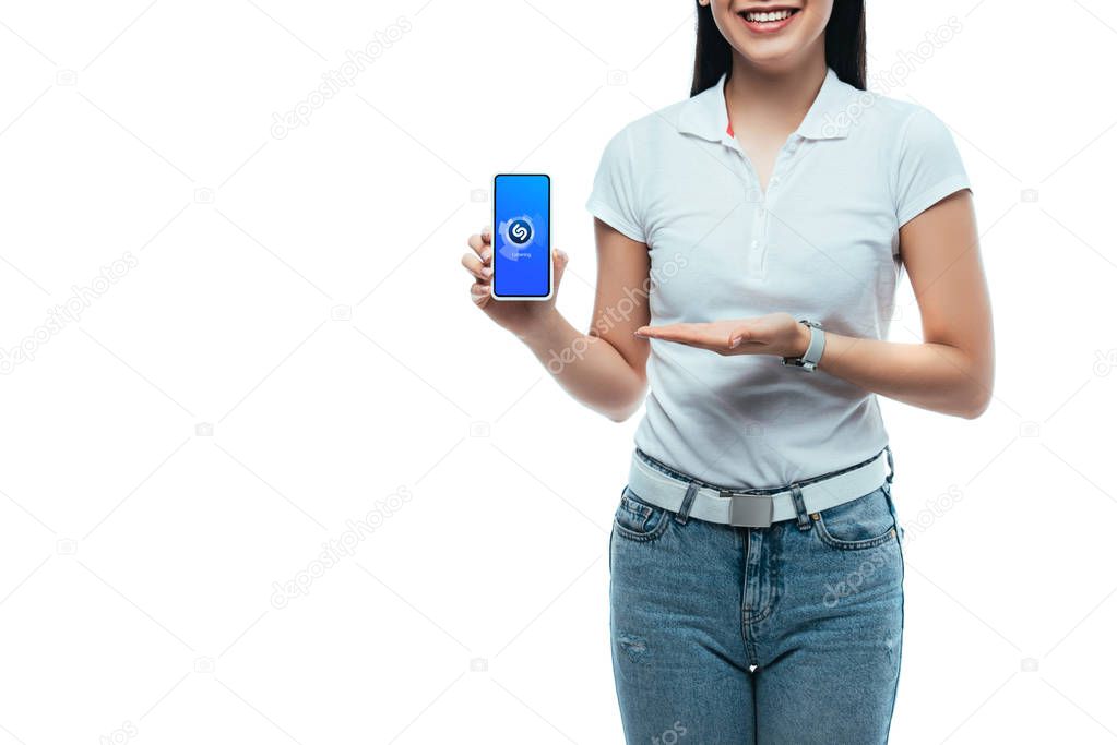 KYIV, UKRAINE - JULY 15, 2019: cropped view of happy brunette asian woman presenting smartphone with shazam app isolated on white
