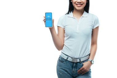 Kyiv, Ukrayna - 15 Temmuz 2019: Beyaz üzerine izole edilmiş Skype uygulamalı akıllı telefon tutan gülümseyen esmer Asyalı kadın görüntüsü