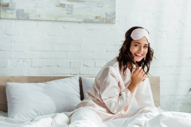 Uyuyan maskeli bir kadın sabah kameraya bakıyor. 