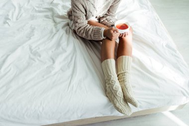 Gri kazaklı bir kadının elinde çay fincanı vardı. 