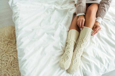 cropped view of woman taking on knitted socks at morning  clipart