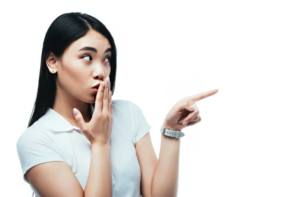 驚くべき魅力的なアジア系の女の子が手で口を覆い白に孤立した指で指差す — ストック写真