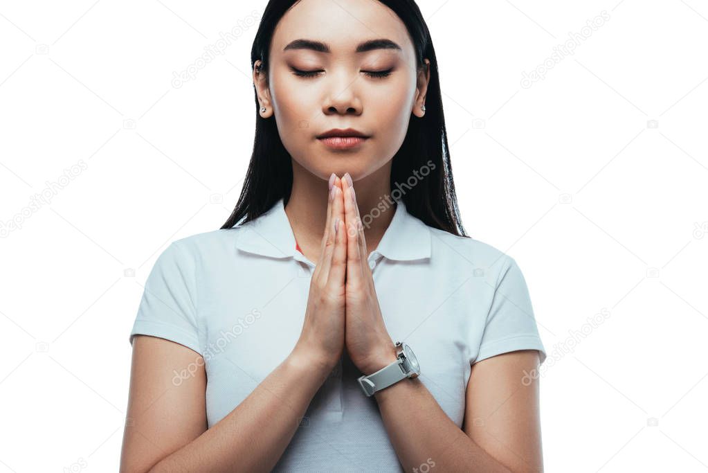 attractive asian girl with closed eyes and praying hands isolated on white