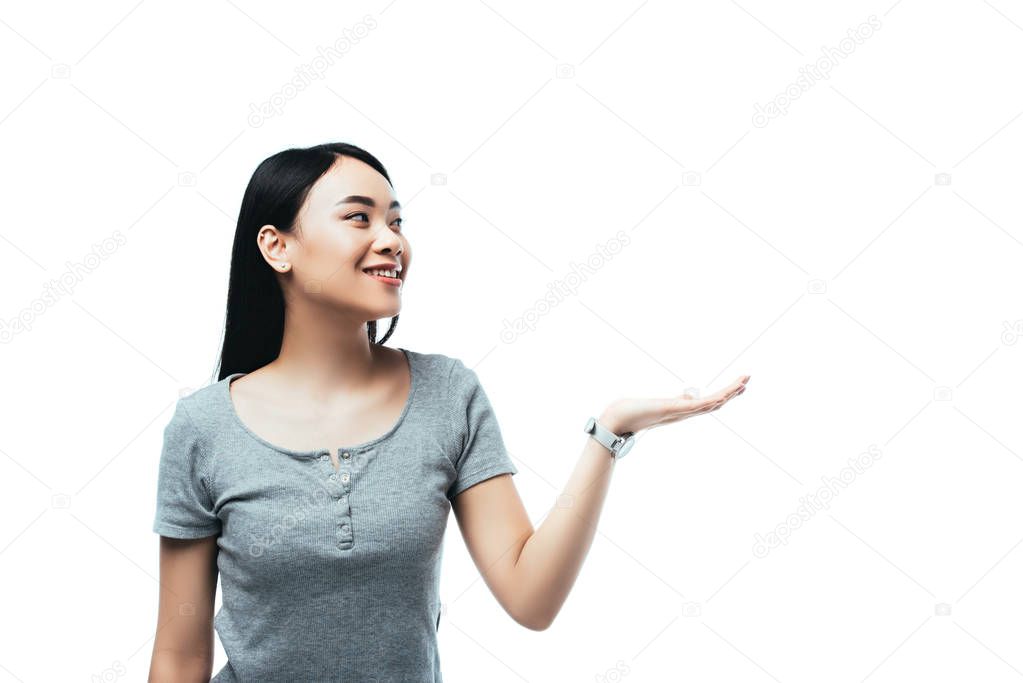 smiling asian girl pointing with hand away isolated on white