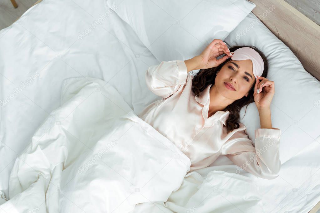 top view of attractive woman in sleeping mask lying in bed at morning 