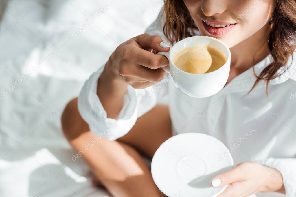 cropped view of woman drinking coffee from cup at morning 