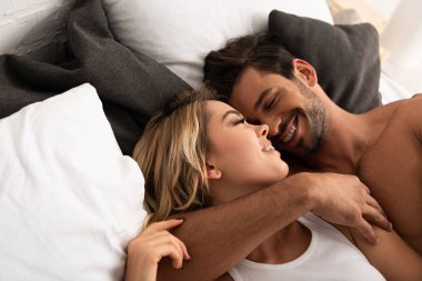 Güler yüzlü çift sabahları yatakta sarılıyor. 